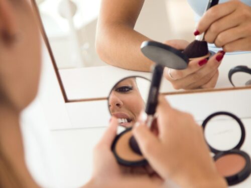 Beautiful young woman making make up near mirror home (1)